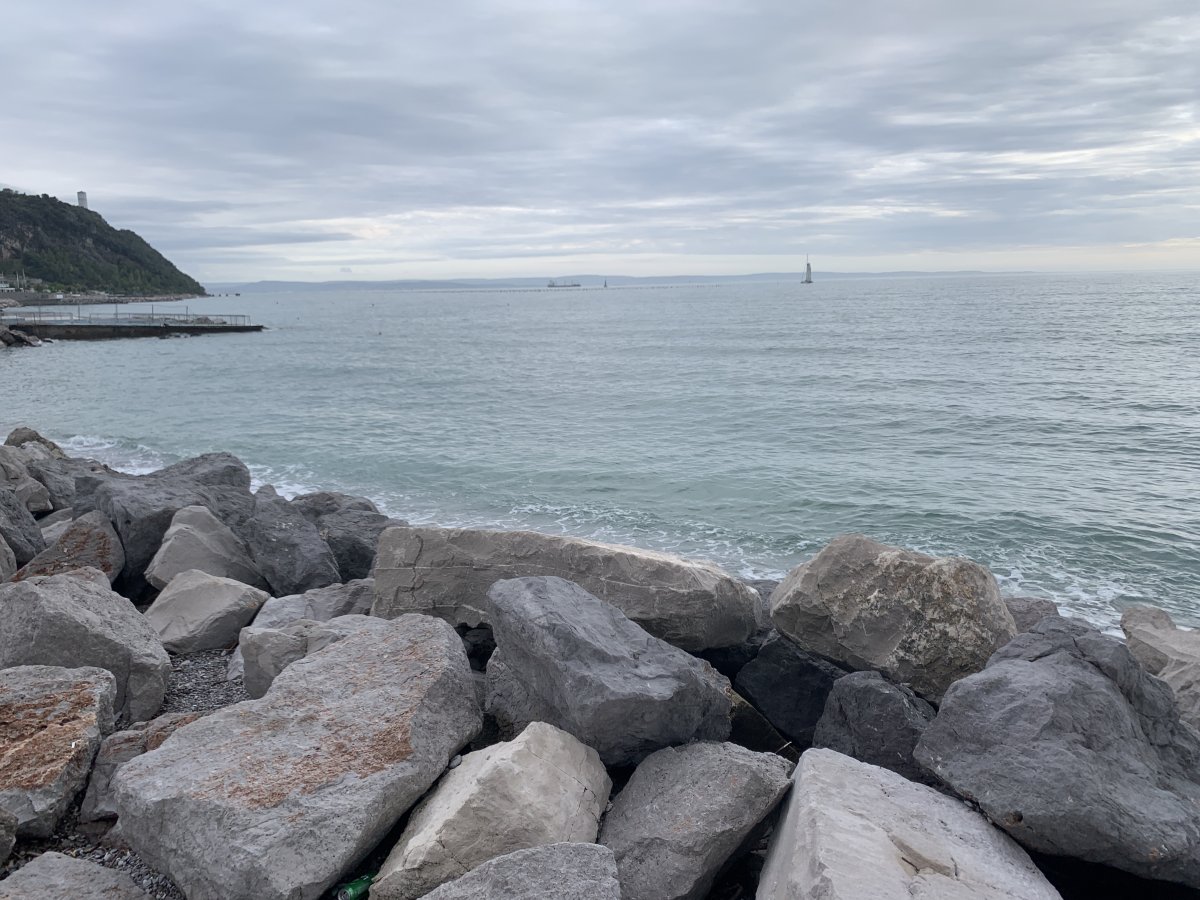 Rock defences at Sistiana harbour, long pebble beach to the left..